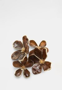 Brun blommig brosch med glänsande kronblad, guldfärgade konturer och detaljerade mittaccents. Har flera lager och varierande kronbladsformer.