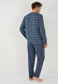 Heren lounge set met een gestreept shirt met lange mouwen in marineblauw en bijpassende zachte, donkerblauwe broeken. Eenvoudig ontwerp met een comfortabele pasvorm.