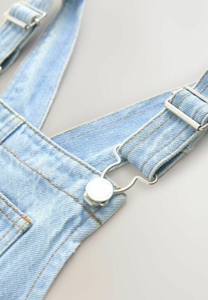 Ljusblå denimhantverksbyxor med justerbara band, silverfärgade metalclips och kontrasterande sömmar. Mjuk textur och avslappnad design.