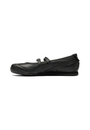 Black leather flat shoe with two adjustable straps, scalloped edge detailing, and textured sole. Sleek design suitable for casual wear.