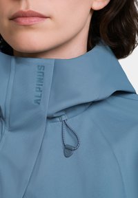 Jasnoniebieska kurtka przeciwdeszczowa z wysokim kołnierzem, regulowanym sznurkiem, teksturowanym materiałem i wytłoczonym logo "ALPINUS" na klatce piersiowej.