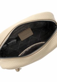 Borsa in pelle color crema con chiusura a zip. L'interno presenta una fodera grigia a motivo e scomparti per l'organizzazione.