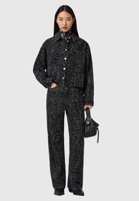 Σετ από μαύρο τζιν μπουφάν και παντελόνι με σχέδιο λεοπάρ. Διαθέτει μεγάλα κουμπιά, γιακά και άνετη εφαρμογή. Τα αξεσουάρ περιλαμβάνουν μια μικρή μαύρη τσάντα.