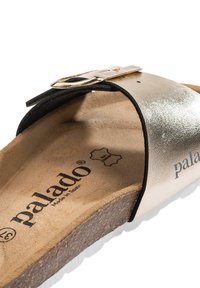 Sandalo a fascia con cinturino metallico dorato e dettagli neri, soletta in sughero e suola bianca texturizzata. Logo impresso sulla soletta.