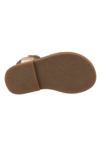 Brown rubber sole with a textured surface, featuring a rounded toe and minimal heel. Upper material includes soft, light-colored fabric accents.