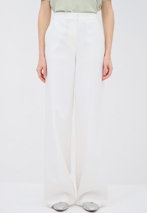 Weiße weite Hosen mit glatter Textur und tailliertem Schnitt, mit hohem Bund und klarem Design. Sichtbares silbernes Schuhwerk.