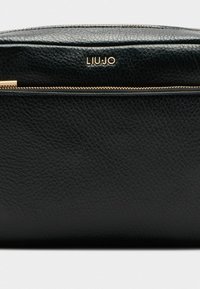 Pochette en cuir noir avec une surface texturée, dotée d'une fermeture éclair en métal doré et du nom de la marque "LIUJO" embossé sur le devant.