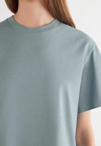 Světle modré bavlněné tričko s kulatým výstřihem a krátkými rukávy, s hladkou texturou a jednoduchým, klasickým designem.