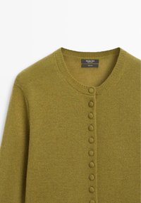 Cardigan en laine vert olive avec encolure ronde et rangée de boutons recouverts sur le devant.