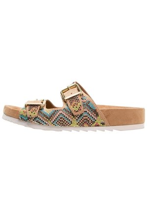 Beżowe zamszowe klapki z kolorowymi ozdobami z dżetów ułożonymi w zygzakowy wzór, z dwoma regulowanymi złotymi klamrami i białą podeszwą.
