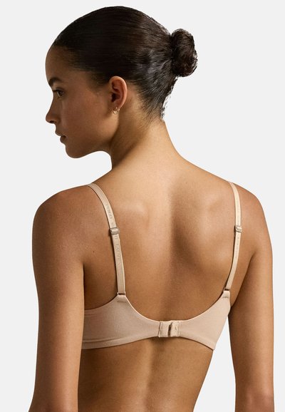 Reggiseno beige con spalline regolabili, una texture liscia e una chiusura a gancio sul retro. Design minimalista, adatto per l'uso quotidiano.