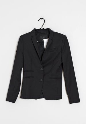 Blazer noir pour femme sur mesure avec deux boutons, col à revers cranté et trois poches avant, suspendu sur un cintre noir sur fond blanc.