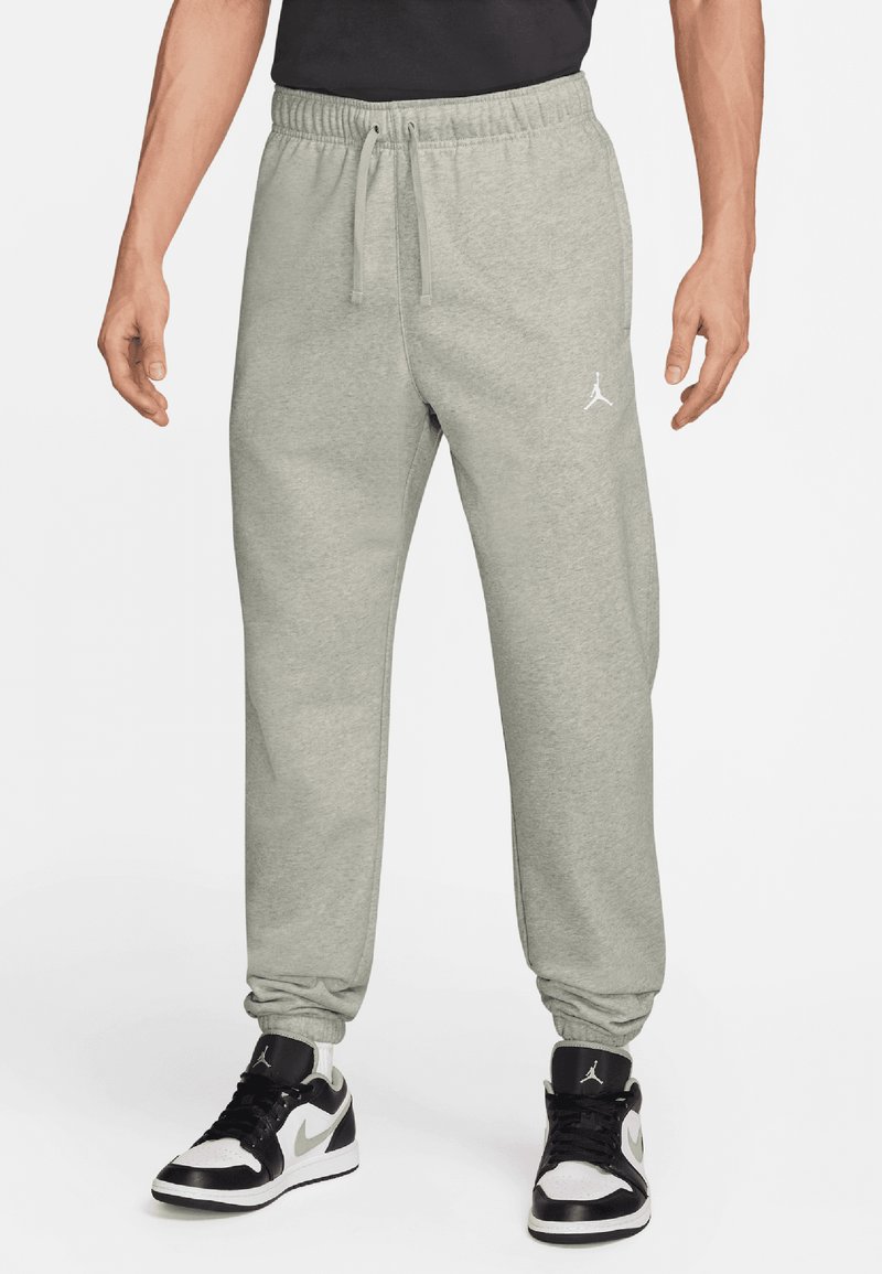 Pantalons de jogging gris avec des poignets et une taille élastiques, présentant un design de logo blanc sur la cuisse gauche, fabriqués en tissu en coton doux.