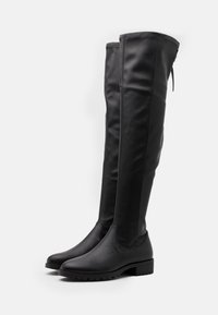Black over-the-knee boots made of smooth synthetic material, featuring a chunky sole, rounded toe, and elasticated back panel for fit.