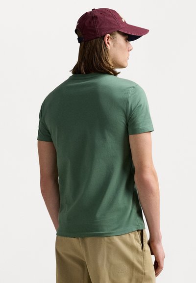 Green short-sleeve t-shirt made of soft fabric. Back view shows a simple design with a rounded neckline and a relaxed fit.