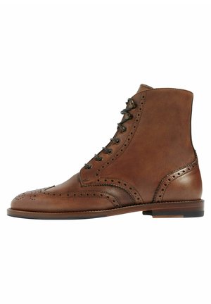 Bottine en cuir marron à lacets de style brogue avec détail ailé et perforations, dotée d'un talon empilé bas et d'une semelle lisse.