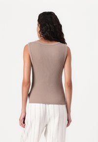 Beige, ribbestrikket ermeløs topp med rund hals og tettsittende design, sett fra bak. Har glatt tekstur og minimale sømmer.