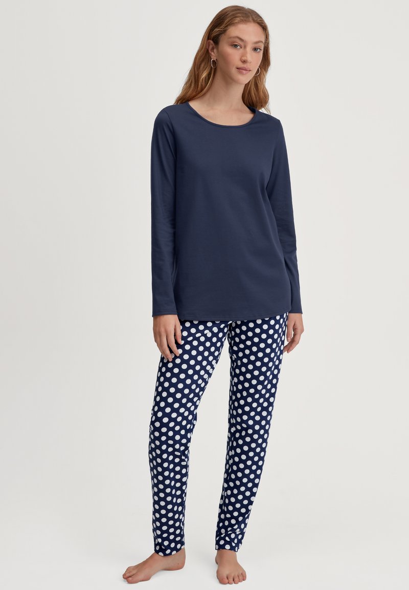 Marineblauw lang hemd met ronde halslijn, gecombineerd met marineblauwe pyjamabroek met stippen in wit en een slankfit ontwerp.
