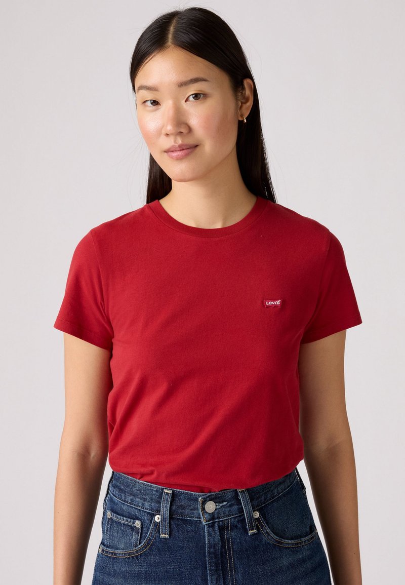 Rød bomull T-skjorte med korte ermer, rund hals og liten Levi's-logo på venstre bryst. Kombinert med høyt liv, denimblå jeans.