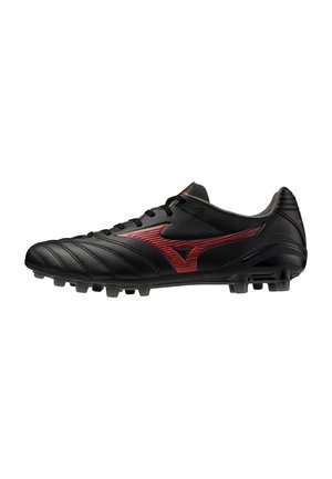 Taco de fútbol negro con logotipo rojo y costuras, con tacos moldeados en la suela para tracción sobre césped.