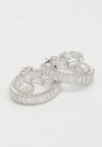 Silver hoop earrings featuring clear rectangular and round crystals, with a central white pearl and intricate detailing on the outer edges.