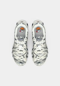 Zapatillas Nike Air Max con un patrón de camuflaje en blanco, gris y negro, que cuentan con una puntera redondeada, diseño de cordones y suela acolchada.