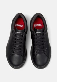 Black leather sneakers featuring round toes, black laces, and red insoles with the "CAMPER" logo prominently displayed.