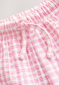 Pantaloni scurți de pijama în carouri roz și alb, cu talie elastică adunată și șnur reglabil. Textură moale cu detalii în dungi verticale.