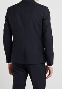 Marineblazer mit tailliertem Schnitt, schmalen Revers, einer Rückenventilation und Knopfmanschetten. Hergestellt aus einem glatten, leichten Stoff.