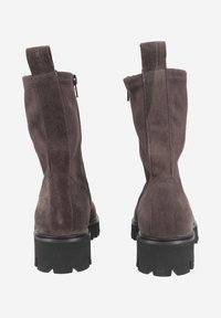 Bottines en suede brun avec une semelle en caoutchouc noir robuste, dotées d'une fermeture éclair et d'une languette à l'arrière pour un enfilage facile.