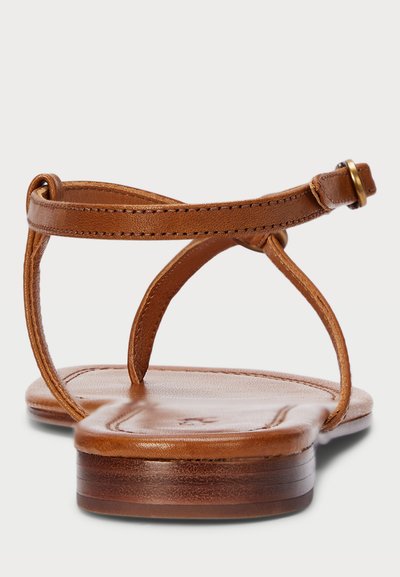 Sandálias de couro castanho com um design minimalista. Apresentam tiras finas, uma tira traseira no tornozelo e uma sola lisa e plana.