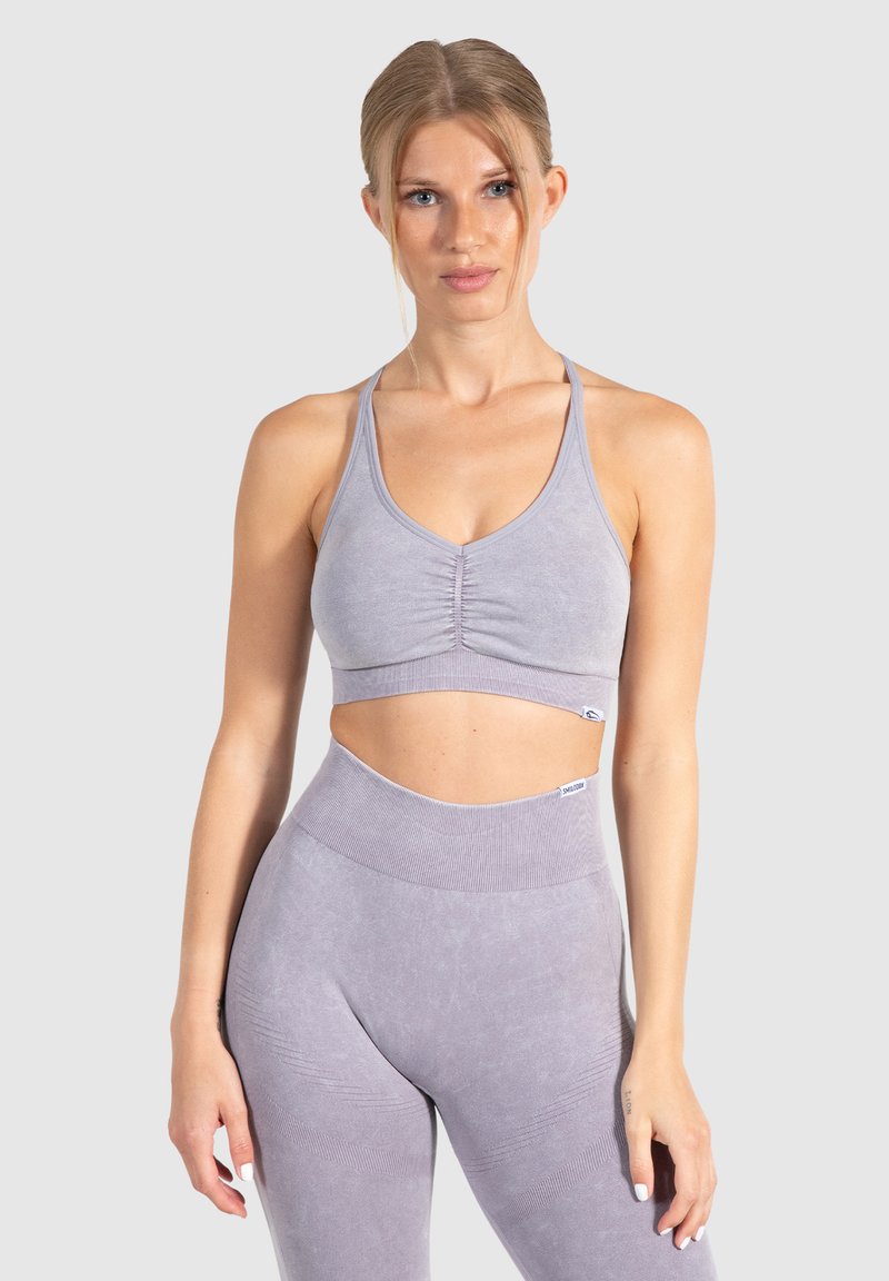 Licht paarse sportbeha met een afgestemde middennaad, verstelbare bandjes en een nauwsluitend ontwerp. Gecombineerd met bijpassende high-waisted legging.