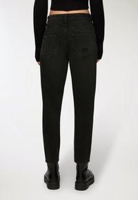 Czarne dżinsy o slim fit, z dwiema tylnymi kieszeniami i lekko wypłukanym wyglądem. W zestawie z czarnymi botkami za kostkę.
