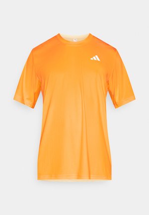 Krótki rękaw pomarańczowej sportowej koszulki wykonanej z lekkiego, gładkiego materiału, z białym logo na górnej lewej stronie.