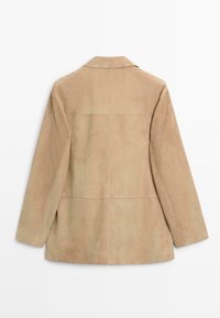 Veste en daim beige à manches longues, col et détails de panneaux cousus, vue de dos sur fond blanc.