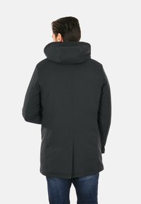 Giacca nera imbottita con un grande cappuccio pieghevole. Design elegante, texture liscia e un'orlo posteriore leggermente più lungo per una maggiore copertura.