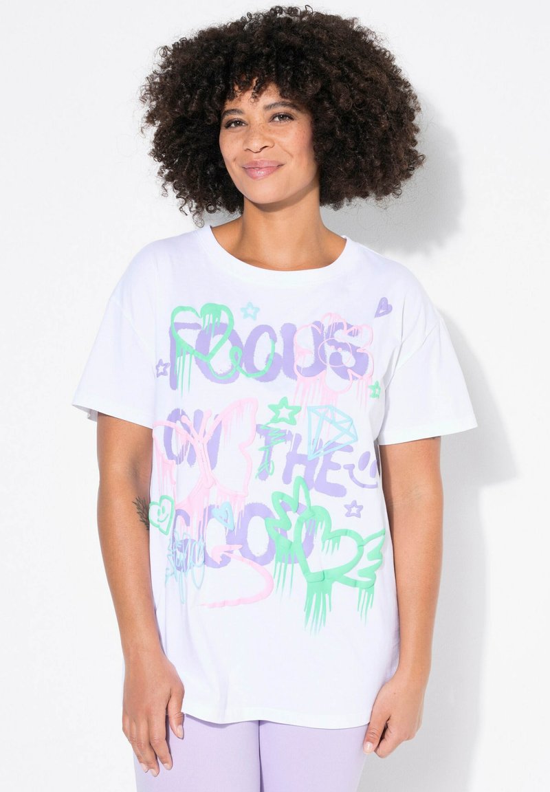 Hvid bomulds T-shirt med farverigt graffiti-lignende tekst i pink, grøn og lilla, samt former som hjerter og stjerner. Korte ærmer.