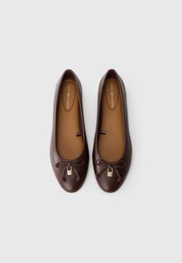 Barna bőr balettcipők kerek orral, díszített masnival és kis arany záróelemmel, bézs belsővel és diszkrét márkajelzéssel.
