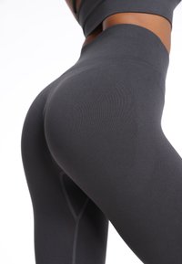 Wysokiej talii, ciemnoszare legginsy wykonane z elastycznego materiału z teksturowanymi panelami i płaskimi szwami dla gładkiego dopasowania.
