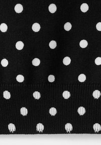 Tissu noir tricoté avec un motif de pois blancs régulièrement espacés et un bord côtelé en bas.