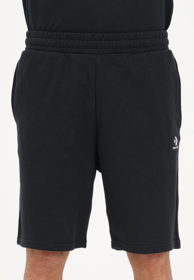 Pantaloni scurți negri dintr-un material moale, cu un tiv elastic, buzunare laterale și un mic logo pe piciorul inferior.