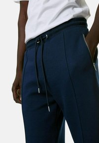 Pantalones de chándal azul marino fabricados en una mezcla de algodón, con una cintura elástica con cordón, bolsillos laterales y una textura suave.