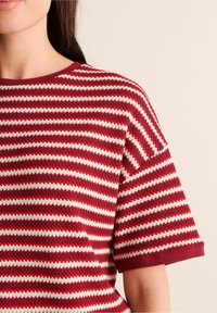 Rot- und cremefarbener gestreifter Strick-T-Shirt mit Rundhalsausschnitt, kurzen Ärmeln und strukturiertem Finish. Mit einem weinroten Saum an den Ärmeln.