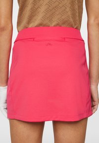 Roze golfrok met een gladde afwerking, voorzien van een subtiele geborduurde logo aan de achterkant en een eenvoudig ontwerp van de tailleband.