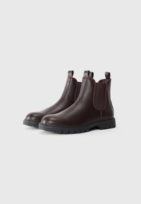 Botas Chelsea de cuero marrón con paneles laterales de elastano y tiradores. Acabado texturizado, punta redondeada y suelas de goma con tacos.