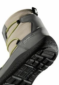 Szary wodoodporny but z teksturowaną, jasnobrązową cholewką, zielonymi elastycznymi sznurowadłami oraz solidną czarną podeszwą z głębokim bieżnikiem zapewniającym przyczepność.
