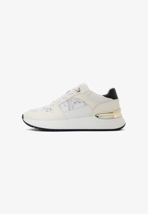 White sneaker featuring a textured white upper, black heel accent, gold hardware detail, and a thick white midsole with black outsole.