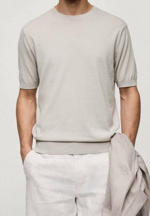Pull beige clair en maille avec manches courtes et col rond, doté d'un col et d'un ourlet côtelés, associé à un pantalon en lin blanc à coupe décontractée.