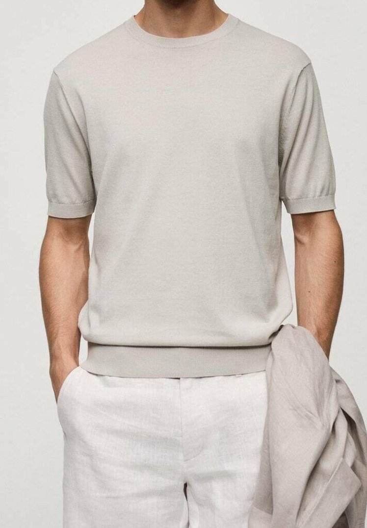 Pull beige clair en maille avec manches courtes et col rond, doté d'un col et d'un ourlet côtelés, associé à un pantalon en lin blanc à coupe décontractée.