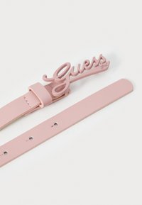 Ružový kožený opasok z umelého materiálu so stylizovanou sponou v podobe loga "Guess", s hladkým povrchom a piatimi nastaviteľnými otvormi na prispôsobenie veľkosti.